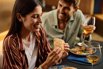 Happy woman and her boyfriend eating together in restaurant.