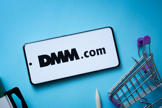 Dhaka, Bangladesh- 03 Oct 2025: Smartphone displaying Dmm.com logo with shopping cart on a blue background.