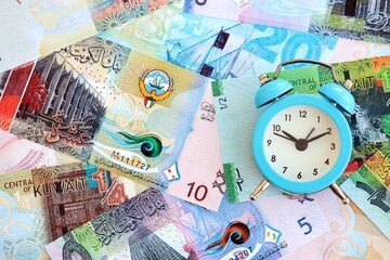 Kuwaiti dinar currency money bills and alarm clock. The concept of time management and income