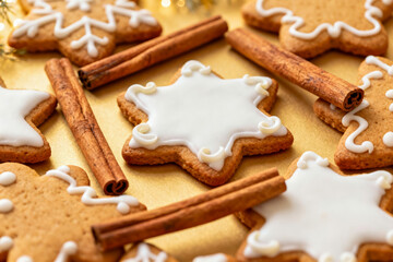 Holiday baking with gingerbread cookies decorated with icing and cinnamon sticks on a golden background