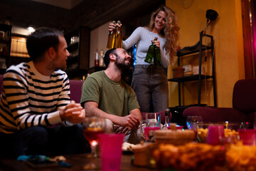 Group of friends socializing with drinks and snacks in a cozy living room setting