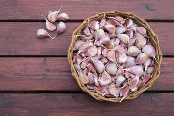 Garlic cloves filling basket on rustic wood surface