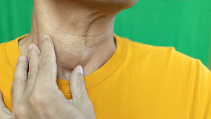 Thyroid gland inflammation at neck, goiter, throat cancer, sore throat and cough, man with neck pain on green, neck health problems concept