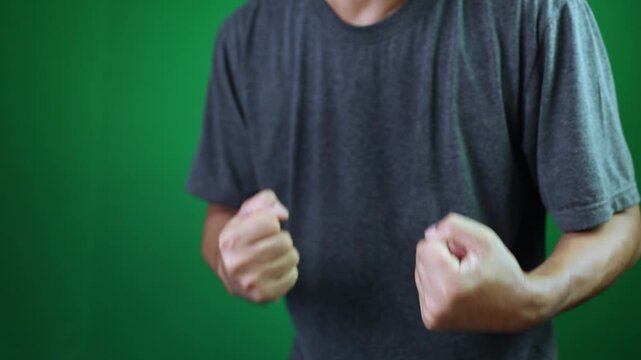 man clenching fists with joy and excitement, expressing success, victory, celebration, positive energy, and strong confidence, green screen background