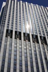 sun reflection on windows of modern very tall skyscraper in financial district