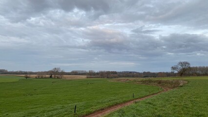 Chemin boueux traversant les champs en fin de journée sous les nuages gris à Écaussinnes d'Enghien (Soignies)