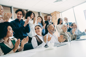 A diverse team of professionals enthusiastically applauding during a productive meeting in a modern office setting
