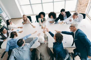 Diverse team joining hands in a collaborative office meeting showcasing teamwork and mutual goals...