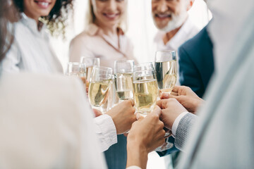 Group of professionals toasting with champagne glasses in a modern office environment during a celebratory event © deagreez