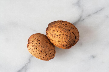 Close-up of almonds with their shells on white marble