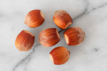 Close-up of hazelnuts in their shells on white marble