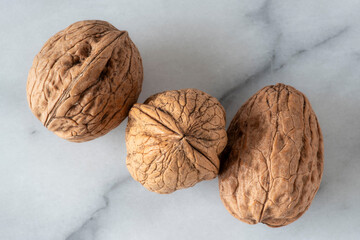 Close-up of walnuts in their shells on white marble