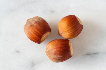 Close-up of hazelnuts in their shells on white marble