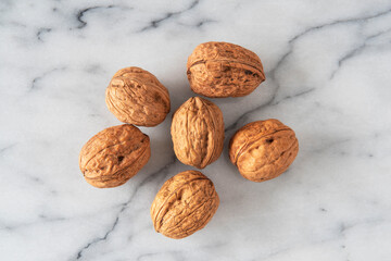 Close-up of walnuts in their shells on white marble