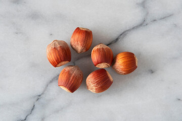 Close-up of hazelnuts in their shells on white marble