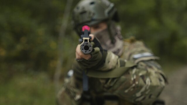 Camouflaged army soldier with AR15 carbine. Rifle with a collimator aiming at the camera. Selective focus. Military war recon