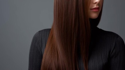 A close-up of a woman with long, shiny hair in a black turtleneck.