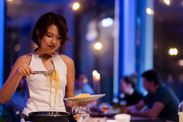 Young woman serving pasta at a warmly lit evening gathering