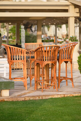 Bar on a beach with wooden bar chairs, table and blurred background of a hotel. Outdoor. Shallow depth of field.	
