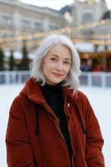 Obraz premium Mature caucasian woman in winter coat smiling outdoors with festive lights