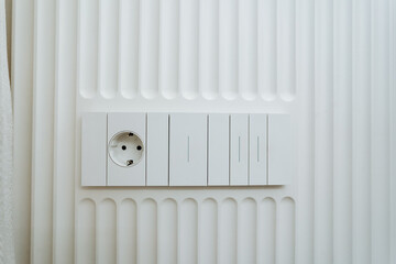 In a modern apartment, sleek electrical outlets and light switches on a textured wall blend functionality and aesthetics, ideal for any renovations or upgrades you are considering