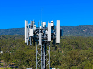 Drone aerial photograph of the top section of a large Telecommunications Tower located in a residential area amongst lush bushland in regional NSW, Australia.