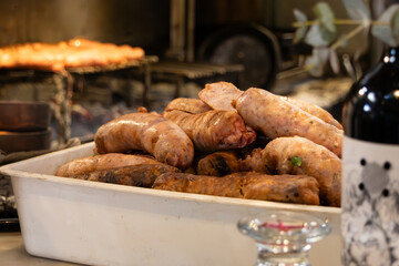 A portion of roasted sausage inside a white container, many elements of the photo are out of focus.