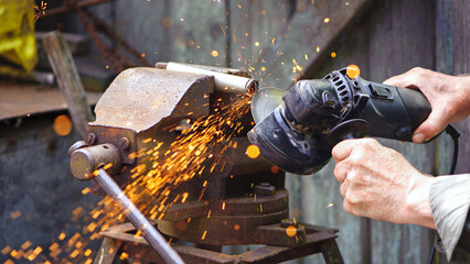 Heavy industry worker cutting steel with angle grinder. Cutting an old rusty pipe. dismantling. close-up. old pipe and work with grinder. hands of a master, professional. sparks of hot metal fly