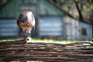 Beautiful handcrafted Ukrainian ceramic pots and jugs are decorating a traditional wicker fence in the countryside, showcasing the beauty of Ukrainian rural life. close-up