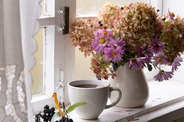 hydrangea and asters in a vase on the window