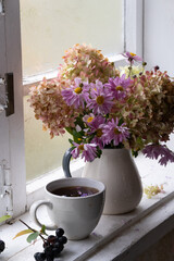 hydrangea and asters in a vase on the window