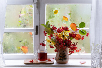 a bouquet of autumn flowers and leaves on window