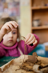 A preschool girl is engaged in clay modeling in a ceramics class. Every Saturday, the children are eager to go to their ceramics class and create pottery.