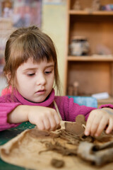 A preschool girl is engaged in clay modeling in a ceramics class. Every Saturday, the children are eager to go to their ceramics class and create pottery.