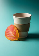 Eco-Friendly Coffee Cup with Autumn Leaf on Teal Background