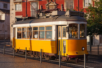 Lisbon, Portugal - July 27, 2025: A classic fampus  yellow tram passes by vibrant red historic...