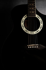 Strumming melodies with a classic black acoustic guitar in soft lighting