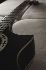 Strumming a beautiful black guitar on a cozy couch in soft evening light