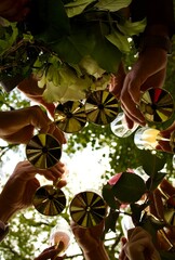 A group of people raising golden-stemmed glasses in a celebratory toast against the backdrop of green leaves and sky, creating joy and unity.