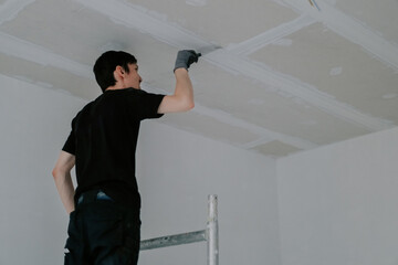 One young worker is cleaning the ceiling with a spatula.
