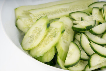 Cucumber cuts and slices in white bowl close up