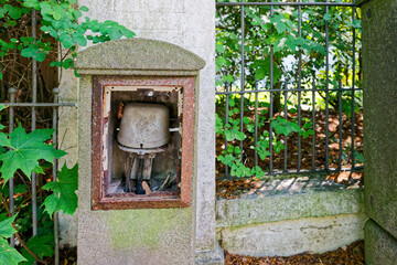 Old concrete post with open utility box and tangled wires