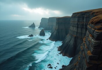 Dramatic Cliffs Overlooking Rugged Coastline with Ocean Waves Crashing Against Rocks Undercloudy Sky