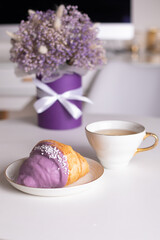 Cup of tea and berry croissant, bouquet of violet flowers