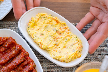 Creamy cheese spread served on a small dish, complemented by savory sides during a casual gathering