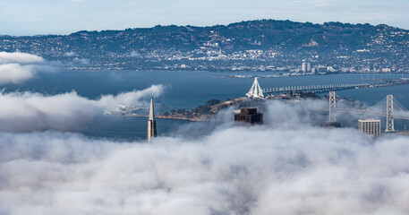 Aerial view of San Francisco featuring the Transamerica Pyramid in fog, the Bay Bridge's eastern...