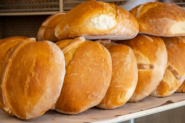 Freshly baked bread rolls piled high on a wooden surface in a warm bakery setting