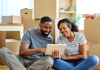 Portrait of a young couple unpacking, moving in and relocation to a new apartment, happy young couple  using a tablet, browsing and shopping online, , family new beginning sitting on the floor
