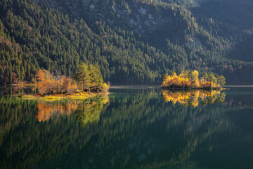 Fototapeta premium Fabulous autumn landscape of islands with pine-trees in the middle of Eibsee lake.