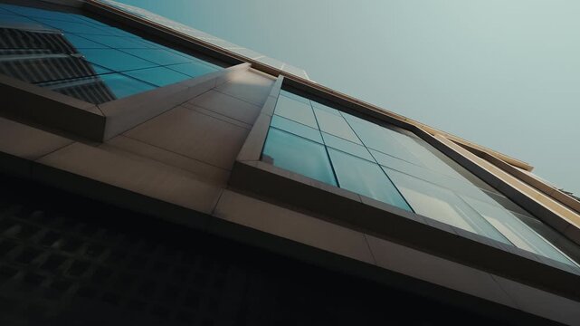 Glass windows on facade of contemporary business center reflect cityscape in downtown low angle shot. Modern commercial urban architecture for business company offices in city